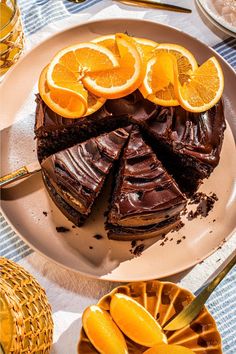 there is a chocolate cake with orange slices on the plate and silverware next to it