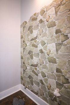 a stone wall with wood flooring next to it and a light on the side