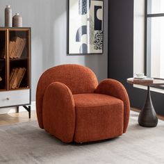 an orange chair sitting on top of a rug in front of a book case and table