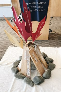 a sculpture made out of wooden sticks and stones on top of a white table cloth