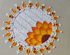 a white doily with an orange and yellow flower in the center on a table