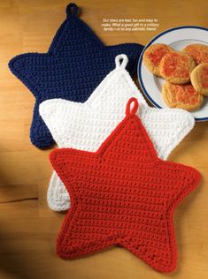 three crocheted stars are on the table next to a plate with cookies in it