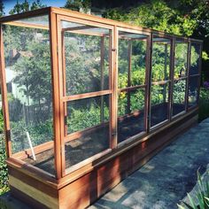 a wooden structure with several windows and plants in it