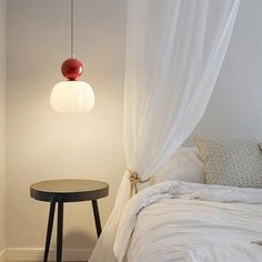 a bedroom with a bed, table and white drapes on the windowsills