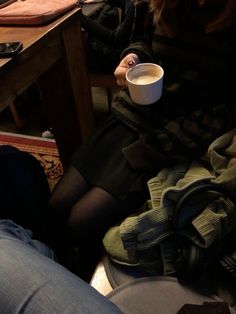 a woman sitting at a table holding a cup of coffee