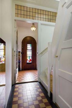 an entry way leading into a house with tiled flooring and white walls, along with a checkered door