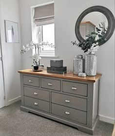 a dresser with drawers and vases on top of it in front of a window