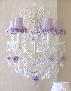 a white chandelier with purple roses on it