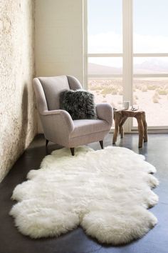 a living room with a chair and a rug on the floor next to a window