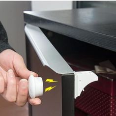 a person is opening the door to an open cabinet with white plastic knobs on it