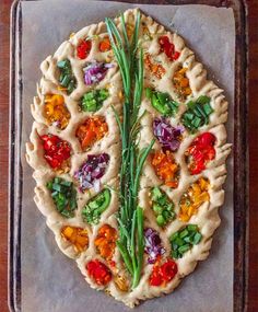 a pizza with vegetables on it sitting on top of a pan covered in wax paper