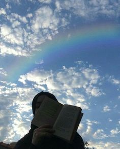 a person reading a book under a rainbow