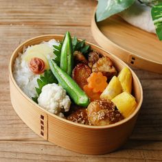 a wooden bowl filled with rice, meat and veggies on top of a table