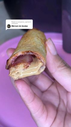 a person holding a half eaten pastry in front of a purple plate with a message on it