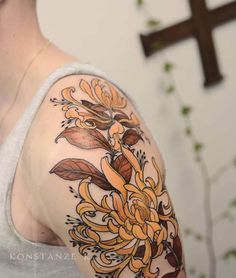 a woman's arm with yellow flowers on it and a cross in the background