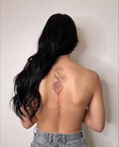 the back of a woman's neck with a flower tattoo on her left shoulder