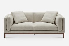 a beige couch with two pillows on it's back and the arms folded down