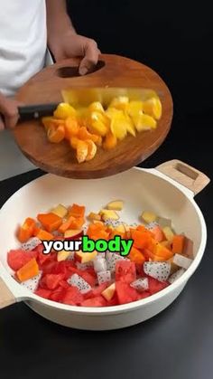 a person cutting up fruit in a bowl with a wooden spatula on the side