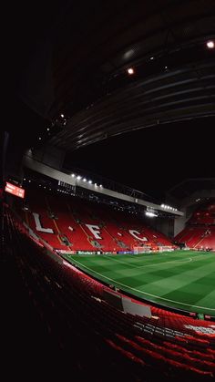 an empty soccer stadium at night with red seats