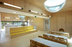 an empty room with tables and chairs in front of the counter, light from above