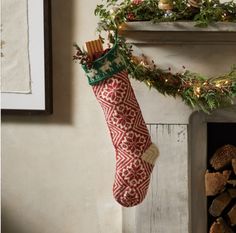 a christmas stocking hanging from a mantel next to a fire place filled with logs