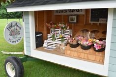 a flower shop with flowers on display in the window and behind it is a wheelbarrow