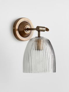 a wall light that is on the side of a wall with a glass shade hanging from it