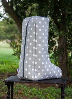 a gray and white polka dot blanket sitting on top of a wooden table next to a tree