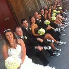 a group of people sitting next to each other in front of a building with flowers