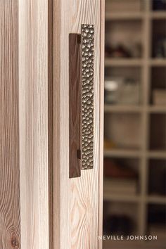 a close up of a door handle on a wooden door with shelves in the background