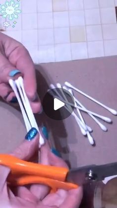 two hands are holding scissors and some toothbrushes