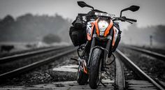 an orange and black motorcycle parked on train tracks