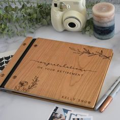 a wooden notebook sitting on top of a table next to a camera and some photos