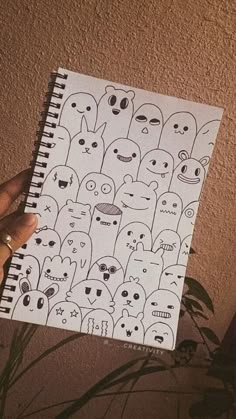 someone holding up a notebook with drawings on it