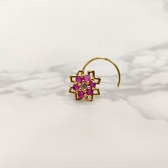 a pair of earrings with pink stones in the center on a marble surface, close up