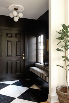 a black and white checkered floor with a potted plant next to the door