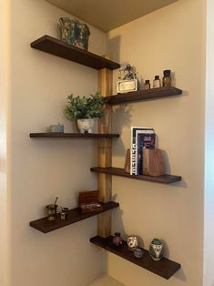 three wooden shelves in the corner of a room with vases and books on them