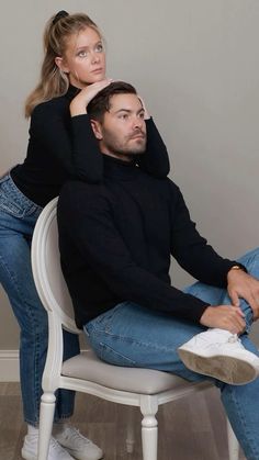 a man sitting on top of a white chair next to a woman in black shirt