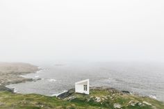 a small white house sitting on top of a lush green hillside next to the ocean