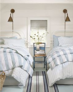 two beds in a bedroom with striped comforters and pillows on the bed, along with a rug