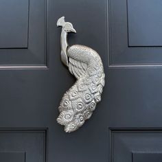 a metal peacock door knocker on a black door