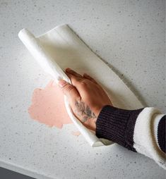 a person's hand on top of a piece of white paper with pink spots