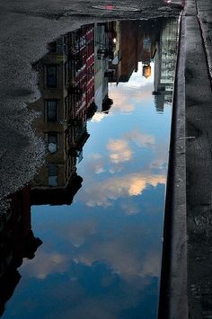 the sky is reflecting in the water on the street