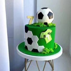 a green and black cake with soccer balls on top is sitting on a white table