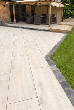 an outdoor patio area with wooden decking and seating on the side, surrounded by green grass