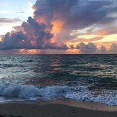 the sun is setting over the ocean with clouds in the sky and waves on the beach