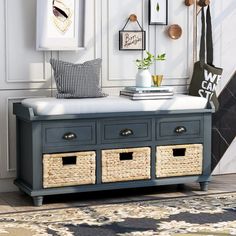 a blue bench with baskets on it in front of a white wall and some pictures