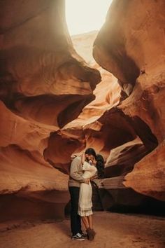 a man and woman standing in the middle of a canyon with their arms around each other