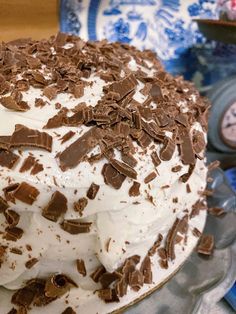 a cake with white frosting and chocolate sprinkles on it sitting on a plate