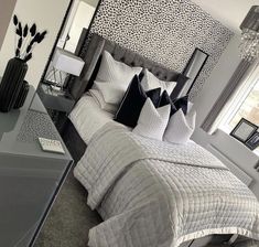 a bedroom with black and white wallpaper, leopard print headboard, grey bedding, gray nightstands, and large mirror